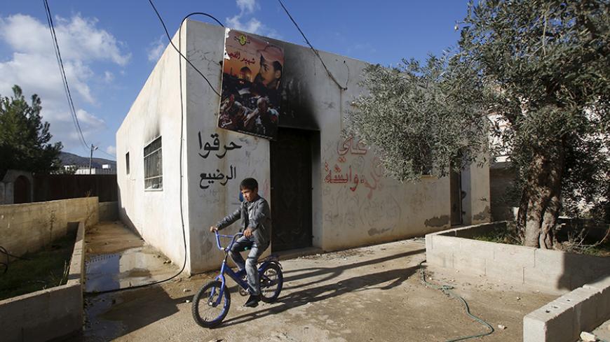 A Palestinian boy rides his bicycle past the Dawabsheh family house near the West Bank city of Nablus, December 3, 2015. Members of a "Jewish terror group" have been arrested over a July arson attack on Dawabsheh home in the Israeli-occupied West Bank that killed a toddler and his parents, Israeli police said on Thursday. REUTERS/Abed Omar Qusini - RTX1X11R