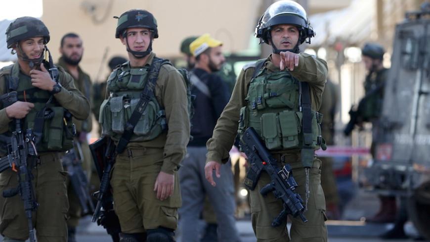 An Israeli soldier gestures as he stands guard with others at the scene of what an Israeli police spokeswoman said was a car-ramming attempt by a Palestinian at the West Bank checkpoint of Qalandia, near Ramallah, December 18, 2015. REUTERS/Mohamad Torokman  - RTX1ZANG