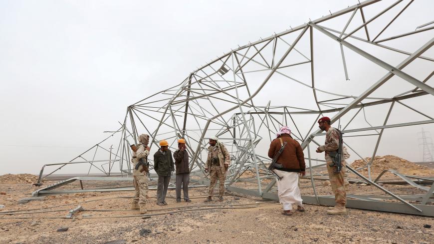 Soldiers loyal to Yemen's government and members of an engineering team stand next to destroyed transmission towers during a search for landmines left by the Houthi rebels in the Mas area, which was taken by pro-government army from the Houthis, in the country's central province of Marib, December 26, 2015. REUTERS/Ali Owidha - RTX203Z5
