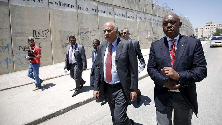 Head of the Palestinian Football Association Jibril Rajoub (2nd R) walks with anti-apartheid activist Tokyo Sexwale (R) past Israel's controversial barrier as they arrive for a news conference in the West Bank town of Al-Ram, near Jerusalem, May 7, 2015. Rajoub reinforced his call for Israel to be suspended from FIFA on Thursday, saying the Israeli Football Association was part of an "apartheid, racist government" that was damaging Palestinian soccer. REUTERS/Mohamad Torokman  - RTX1BZBF