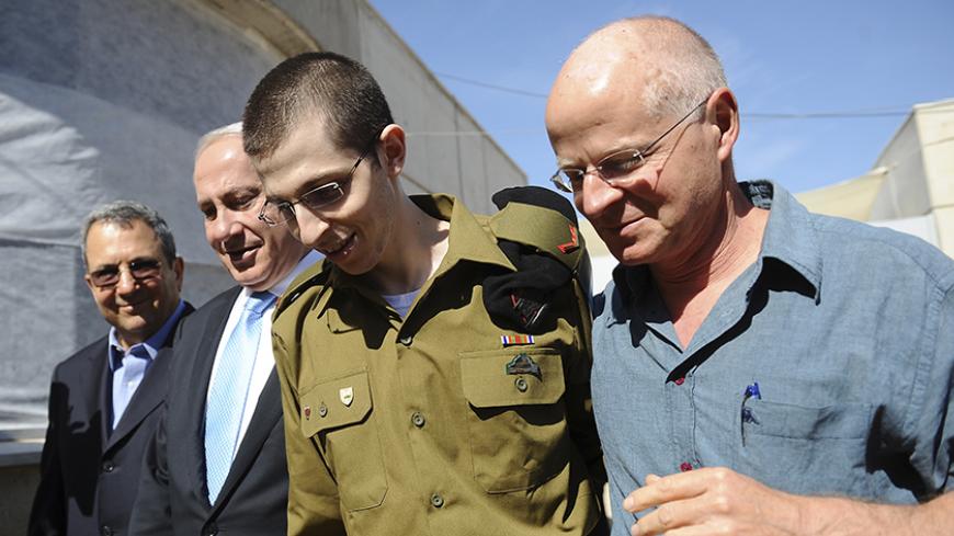 Gilad Shalit (2nd R) walks with his father Noam (R), Israel's Prime Minister Benjamin Netanyahu and Defence Minister Ehud Barak (L) at Tel Nof air base in central Israel in this handout released by the Prime Minister's Office (PMO) October 18, 2011. Israeli soldier Gilad Shalit returned home to a national outpouring of joy on Tuesday after five years in captivity as hundreds of Palestinian prisoners exchanged for him were greeted with kisses from Hamas leaders in the Gaza Strip. REUTERS/PMO/Handout (ISRAEL 