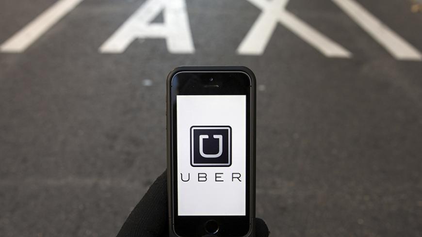 The logo of car-sharing service app Uber on a smartphone over a reserved lane for taxis in a street is seen in this photo illustration taken in Madrid on December 10, 2014. A Madrid judge has ordered U.S.-based online car booking company Uber to cease operations in Spain, the latest ban on the popular service. Taxi drivers around the world consider Uber unfairly bypasses local licensing and safety regulations by using the internet to put drivers in touch with passengers.  REUTERS/Sergio Perez  (SPAIN - Tags