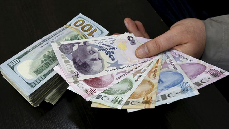 A money changer holds Turkish lira banknotes next to U.S. dollar bills at a currency exchange office in central Istanbul April 15, 2015. Turkish Economy Minister Nihat Zeybekci said on Wednesday the lira's slide to record lows was not a cause for concern and reflected global developments, arguing against forex intervention and saying the currency will find its own balance. He also told a meeting in Istanbul that he expected first quarter year-on-year growth of around 1.5 percent, and full year growth exceed