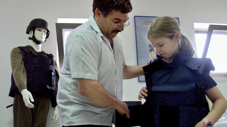 FOR RELEASE WITH FEATURE MIDEAST-SETTLERS - Jewish settler and manager of the Mofaz Etzion bullet-proof vest factory Shamai Ben-Baruch (L) helps his daughter Itamar model a child-sized bullet proof jacket in the West Bank settlement of Gush Etzion, near Hebron. Almost a day does not pass without Jewish settlers being shot at and sometimes killed as they drive on West Bank "bypass" roads. Many settlers are now buying bullet-proof vests to wear when they travel to and from their settlements.

NB - RTRJYGM