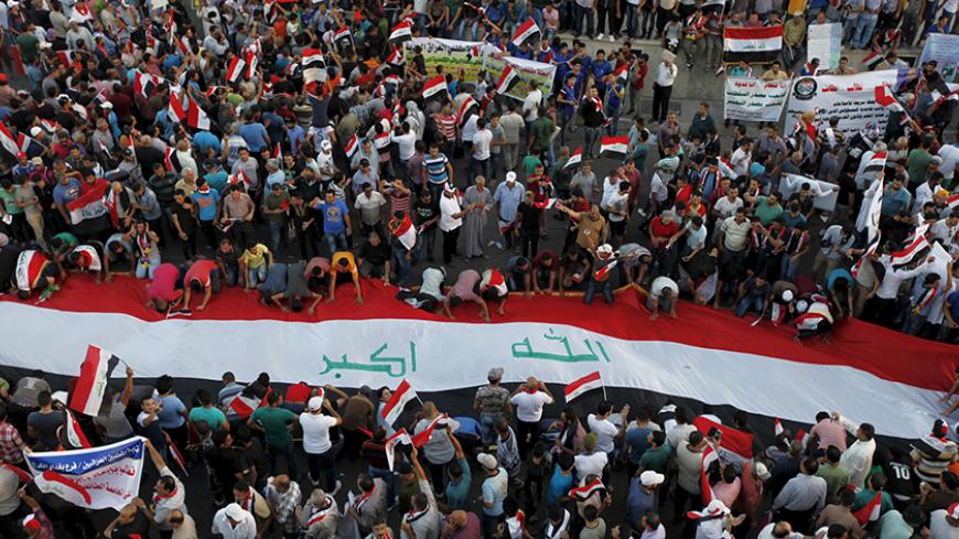 Protesters display a huge Iraqi flag during a demonstration against corruption, poor services and power cuts in Baghdad, Iraq, August 21, 2015.  REUTERS/Ahmed Saad - RTX1P48C