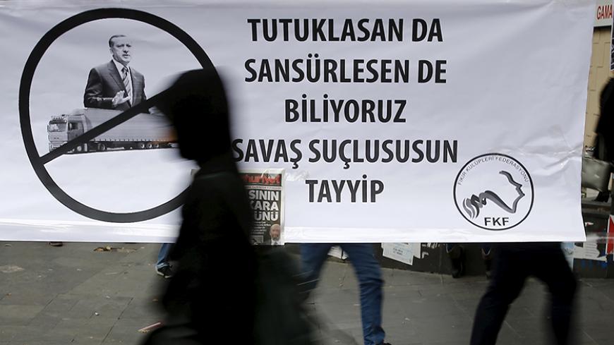 A woman walks past a banner that reads, "Even you arrest (journalists) or censor (media) we know that you are a war criminal Tayyip" and with a picture of Turkish President Recep Tayyip Erdogan during a protest over the arrest of journalists Can Dundar and Erdem Gul in Ankara, Turkey, November 27, 2015. Around 2,000 people protested on Friday over the arrest of two prominent journalists on charges of espionage and terrorist propaganda, a case that has revived long-standing criticism of Turkey's record on pr