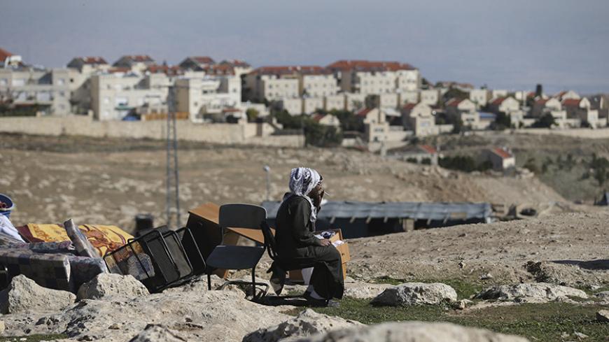 A Palestinian man smokes a cigarette as he sits near his belongings after the Israeli army demolished his shanty, that his family lives in, near the Israeli West Bank settlement of Maale Adumim, near Jerusalem January 6, 2016. The owners of the shanty said they were informed by the Israeli army that the demolition was carried out because they did not have Israeli-issued permits to reside in the area. REUTERS/Mohamad Torokman  - RTX2199M