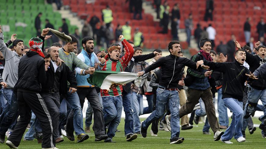 Diyarbakirspor fans shout slogans on the pitch as they hold a burning Bursaspor team flag during a Turkish Super League soccer match between Diyarbakirspor and Bursaspor in Diyarbakir March 6, 2010. The game between Bursaspor and Diyarbakirspor was suspended on the 17th minute on Saturday, when Diyarbakirspor fans began throwing foreign objects to the pitch.    REUTERS/Anatolian/Cem Ozdel (TURKEY - Tags: SPORT SOCCER CIVIL UNREST) TURKEY OUT. NO COMMERCIAL OR EDITORIAL SALES IN TURKEY - RTR2BAW4