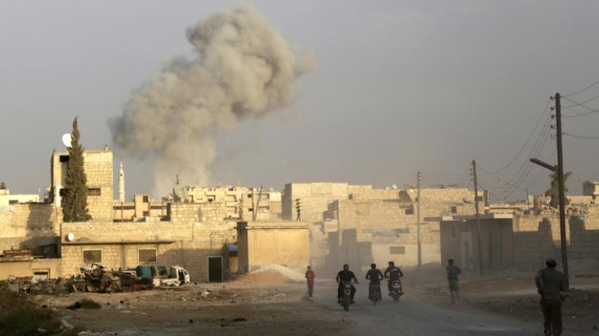 Men ride motorcycles as smoke rises because of, what activists said was, an airstrike carried out by the Russian air force in the rebel-controlled area of Maaret al-Numan town in Idlib province, Syria October 24, 2015. REUTERS/Khalil Ashawi - RTS7RYZ