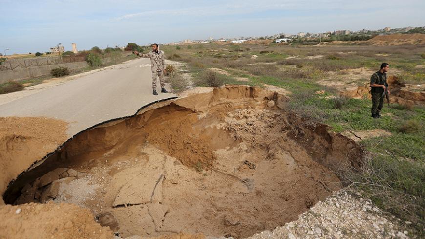Members of the Palestinian security forces loyal to Hamas stand guard as they view a landslide caused by floodwater pumped by Egyptian forces to destroy a network of Palestinian tunnels, near the border between Egypt and southern Gaza Strip November 26, 2015. REUTERS/Ibraheem Abu Mustafa - RTX1VYBN