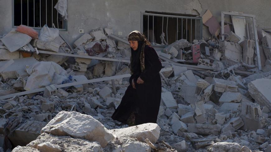 A woman makes her way through the rubble of damaged buildings after airstrikes by pro-Syrian government forces in the rebel held town of Dael, in Deraa Governorate, Syria February 12, 2016. REUTERS/Alaa Al-Faqir - RTX26N2E