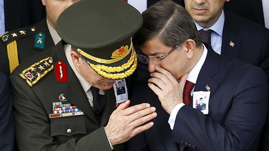 Prime Minister Ahmet Davutoglu (R) chats with Chief of Staff General Hulusi Akar during a funeral ceremony for Army officer Seckin Cil in Ankara, Turkey, February 18, 2016. Army officer Cil was killed during the clashes between Turkish security forces and Kurdish militants in Sur district of the southeastern city of Diyarbakir. REUTERS/Umit Bektas - RTX27IRL