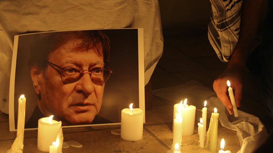 A candle is placed in front of a picture of late Palestinian poet Mahmoud Darwish, during a candle-lit vigil in Amman August 11, 2008. Darwish, whose poetry encapsulated the Palestinian cause, will be buried in the West Bank on Wednesday, a day later than planned, Palestinian officials said. REUTERS/Ali Jarekji  (JORDAN) - RTR20XLG