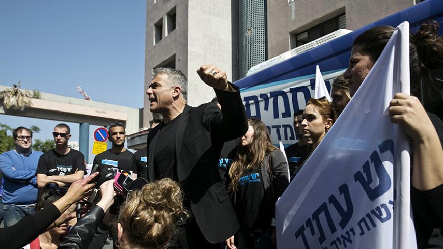 Yesh Atid leader Yair Lapid (C) speaks to members of the media in Tel Aviv before heading on a campaign tour March 15, 2015. Once a heartthrob television news anchor, Lapid, 51, was the rising star of Israeli politics in the 2013 election. His centrist Yesh Atid party came second behind Netanyahu's Likud. REUTERS/Baz Ratner (ISRAEL - Tags: POLITICS ELECTIONS) - RTR4TEHU