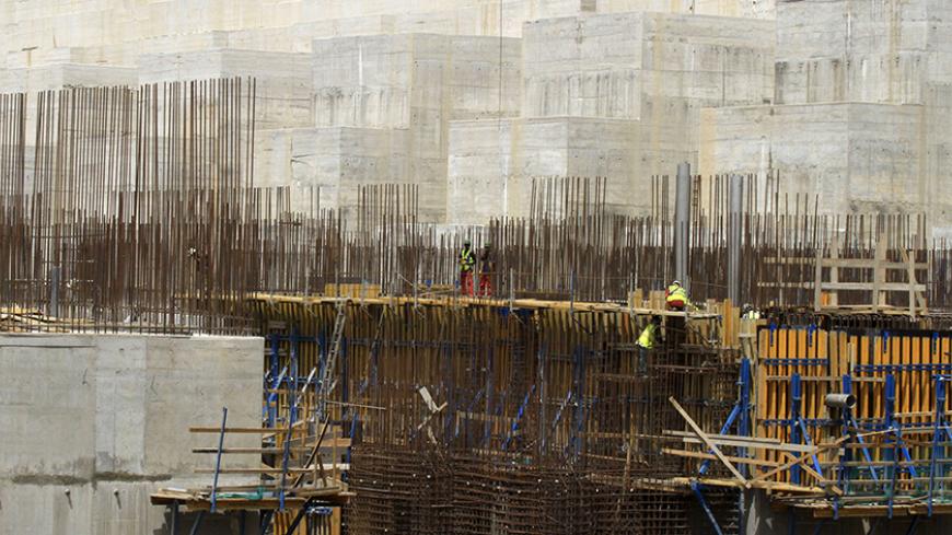 Construction workers are seen at a distance in a section of Ethiopia's Grand Renaissance Dam, as it undergoes construction, during a media tour along the river Nile in Benishangul Gumuz Region, Guba Woreda, in Ethiopia March 31, 2015. According to a government official, the dam has hit the 41 percent completion mark. Picture taken March 31, 2015. REUTER/Tiksa Negeri  - RTR4VQ5S