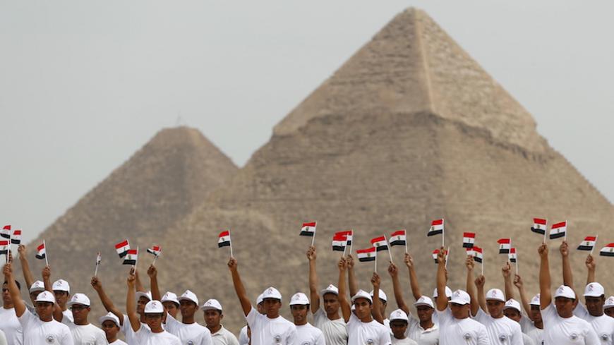 Students from the Egyptian Military Academy hold up Egyptian flags at the opening of the Egyptian International Parachuting Championship, which is organized by the Egyptian Parachuting and Air Sports Federation (EPAF), in front of the Great Pyramids of Giza, Egypt March 2, 2016. REUTERS/Amr Abdallah Dalsh - RTS8YH9