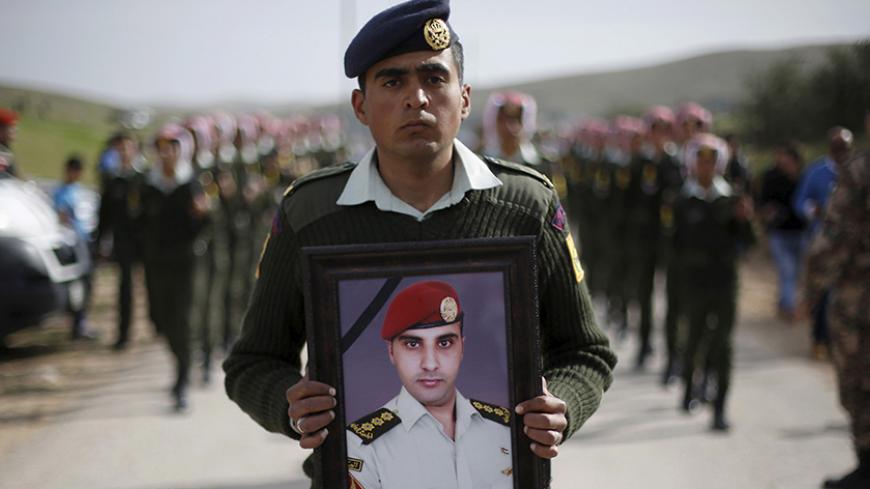A Jordanian soldier carries a picture of Jordanian Captain Rashed Zyoud, who was killed during a raid conducted by the Jordanian security forces on Islamic State militants in Irbid, during the funeral in Zarqa, Jordan, March 2, 2016. REUTERS/Muhammad Hamed - RTS8ZIL
