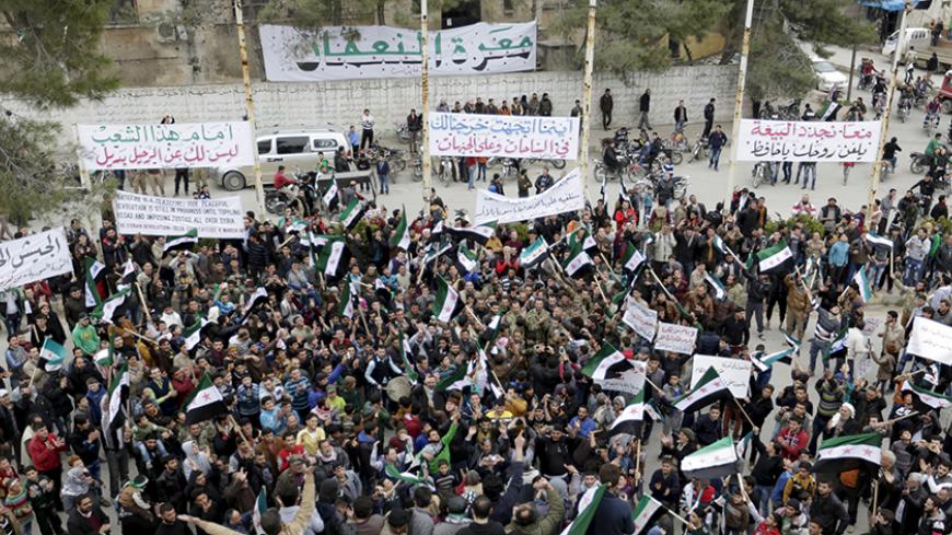Protestors carry Free Syrian Army flags and chant slogans during an anti-government protest in the town of Marat Numan in Idlib province, Syria March 4, 2016. The text on the banners read in Arabic "Together we renew our pledge of allegiance, curse your soul Hafez" (top R), "Wherever you head to, we will go to the squares and the fronts" (top C) and "Before the people, you have no choice but to leave" (top L). REUTERS/Khalil Ashawi - RTS9AYC