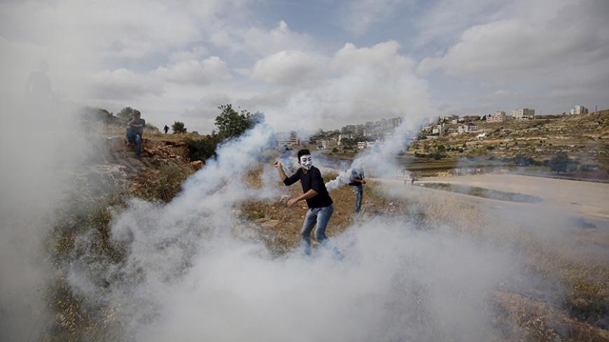 A Palestinian protester returns a tear gas canister fired by Israeli troops during clashes near Israel's Ofer Prison near the West Bank city of Ramallah May 22, 2015. REUTERS/Mohamad Torokman
      TPX IMAGES OF THE DAY      - RTX1E56H