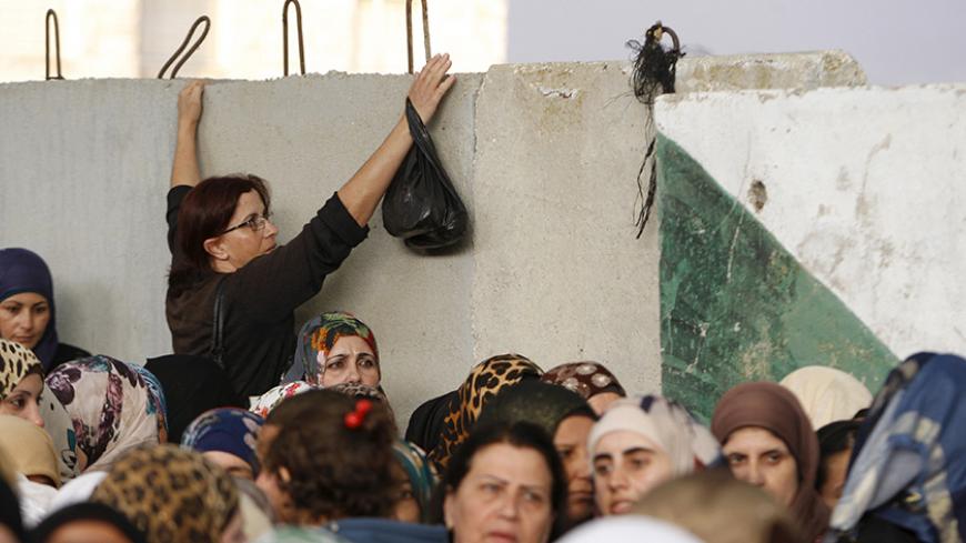 A Palestinian woman tries to bypass others as they make their way to attend the second Friday prayer of Ramadan in Jerusalem's al-Aqsa mosque, at an Israeli checkpoint in the West bank city of Bethlehem June 26, 2015. REUTERS/Mussa Qawasma - RTX1HV77