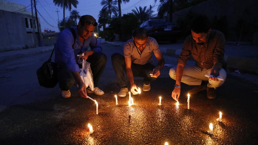 Iraqi journalists light candles at the site where Mohammed Badawi, the Baghdad bureau chief of Radio Free Iraq, was shot dead by a Kurdish officer in Baghdad's Jadriyah district March 22, 2014. Badawi was shot dead by the Kurdish officer at a checkpoint in Baghdad on Saturday as he went to work, provoking protests by other journalists and a promise by Prime Minister Nouri al-Maliki to arrest the perpetrator.  REUTERS/Thaier al-Sudani (IRAQ - Tags: CIVIL UNREST POLITICS MEDIA) - RTR3I6H4