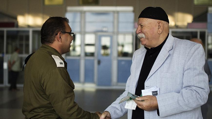 A Palestinian from Gaza shakes hands with an Israeli soldier (L) after receiving a greeting card for Eid al-Adha at Israel's Erez Crossing October 5, 2014. In a rare step Israel said on October 2, 2014 it would let 500 Palestinians living in Gaza pray at a Jerusalem holy site during the Eid al-Adha feast at the weekend, and allow Palestinians from the West Bank to enter Israel more freely for the holiday.The Israeli military said that from Oct. 5 through 7 the days of the Muslim feast, 500 Palestinians from