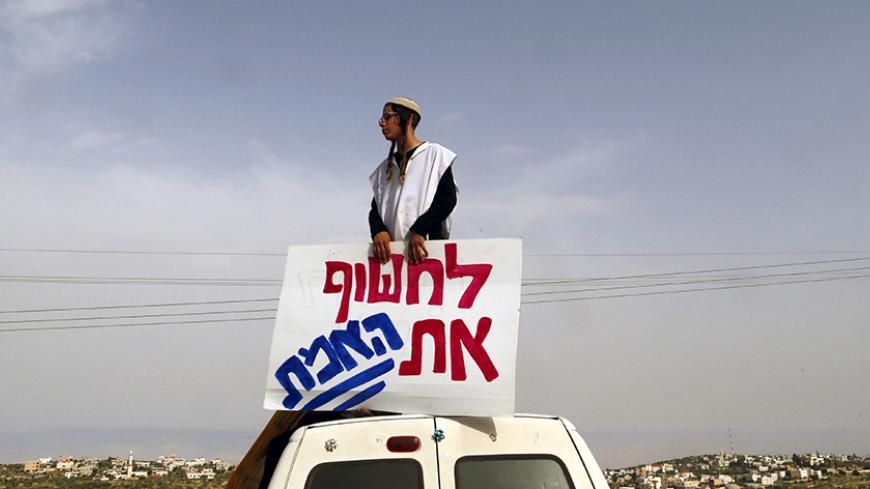 An Israeli right-wing activist takes part in a protest calling for the release of suspected Jewish attackers, who were arrested by Israel over a July arson attack on a Palestinian home that killed a toddler and his parents, outside the West Bank village of Duma near Nablus, April 5, 2016. The Hebrew script reads, "Reveal the Truth". REUTERS/Ammar Awad - RTSDPT1