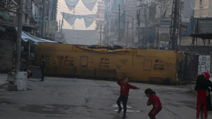 Children play near a bus barricading a street, which serves as protection from snipers loyal to Syria's President Bashar al-Assad, in Aleppo's rebel-controlled Bustan al-Qasr neighbourhood, Syria April 6, 2016. REUTERS/Abdalrhman Ismail - RTSDWK5