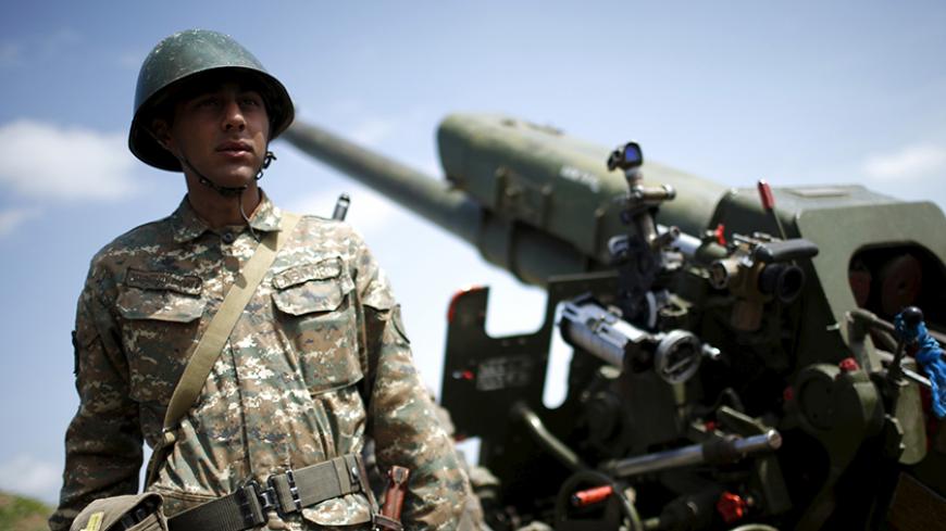 An ethnic Armenian soldier stands next to a cannon at artillery positions near the Nagorno-Karabakh's town of Martuni, April 7, 2016. REUTERS/Staff - RTSDZLE
