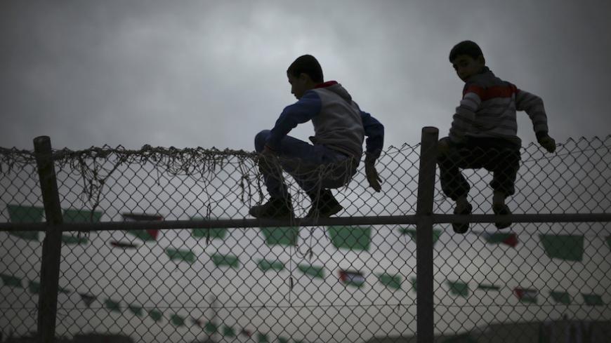 Palestinian boys sit on a fence as they watch a Hamas rally in Khan Younis in the southern Gaza Strip January 7, 2016. The rally, organized by Hamas movement, was held to honor the families of dead Hamas militants, who Hamas's armed wing said participated in imprisoning Israeli soldier Gilad Shalit, organizers said. Shalt was abducted by militants in a cross-border raid in 2006, and was released in exchange for more than 1,000 Palestinians held in Israeli jails. REUTERS/Mohammed Salem  - RTX21FR7