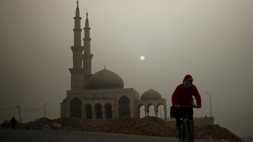 A Palestinian man rides his bicycle in front of a mosque on a stormy day in Gaza January 18, 2016. REUTERS/Mohammed Salem  - RTX22XLX