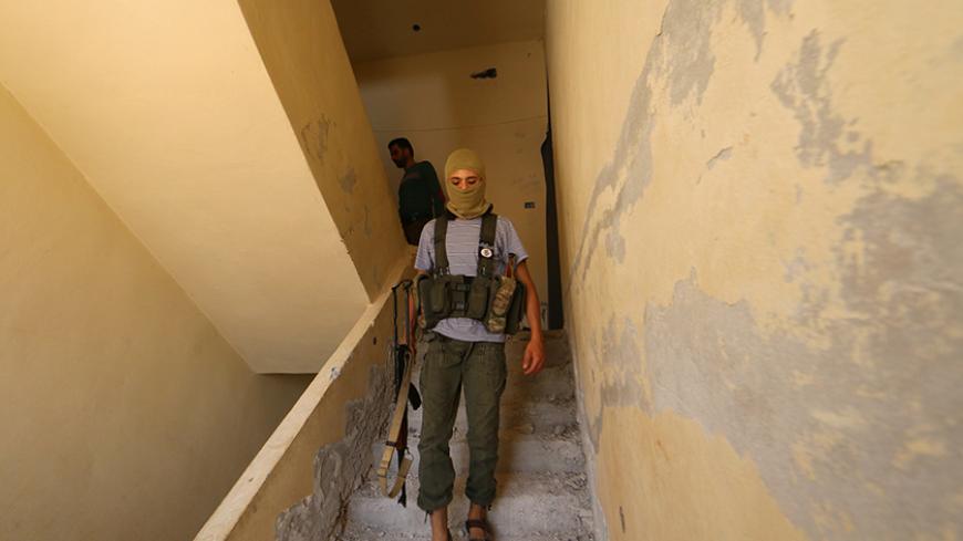 A Nusra Front fighter walks with his weapon inside a building in the Sheikh Maksoud neighbourhood of Aleppo, Syria  August 3, 2015. REUTERS/Abdalrhman Ismail - RTX242Y9