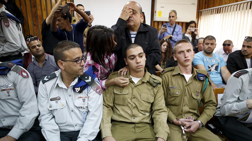 The father (C, back) of Israeli soldier Elor Azaria (C, seated), who is charged with manslaughter by the Israeli military after he shot a wounded Palestinian assailant as he lay on the ground in Hebron on March 24, prays behind him in a military court during a remand hearing for his case, near the southern Israeli city of Kiryat Malachi, March 31, 2016. Picture taken March 31, 2016. REUTERS/Amir Cohen - RTX2AHZ0