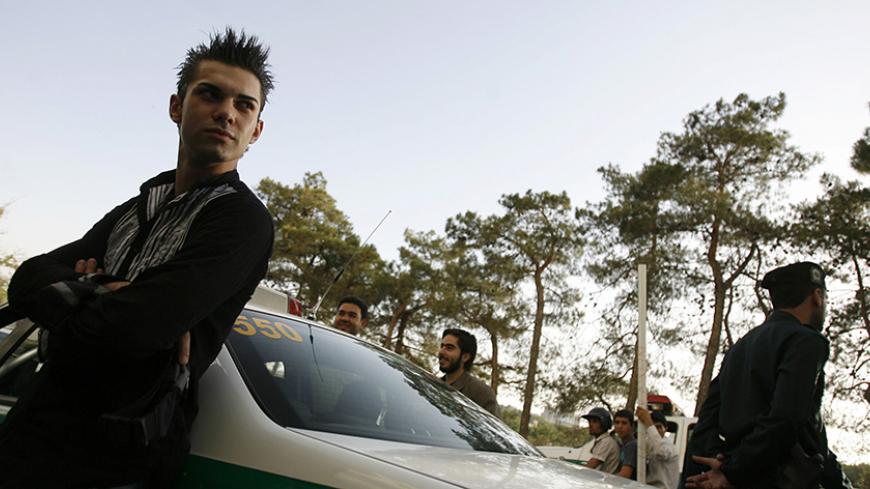A youth leans against a police car after being detained for a Western-style haircut in Tehran June 16, 2008. Iranian police have launched a more extensive crackdown on "social corruption" such as women flouting Islamic dress codes, the Farhang-e Ashti newspaper reported on Monday. The daily also reported that men with Western-style haircuts were confronted by the police and barber shops that gave them such haircuts were sealed off. Picture taken June 16, 2008.  REUTERS/Stringer (IRAN) - RTX71DO