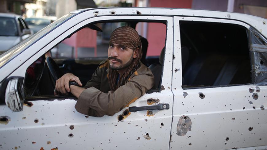 A Palestinian taxi driver sits in his damaged car as he waits for passengers in Gaza City September 22, 2014. An open-ended ceasefire between Israel and Hamas-led Gaza militants, mediated by Egypt, took effect on August 26 after a seven-week conflict. It called for an indefinite halt to hostilities, the immediate opening of Gaza's blockaded crossings with Israel and Egypt, and a widening of the territory's fishing zone in the Mediterranean. REUTERS/Mohammed Salem (GAZA - Tags: POLITICS CIVIL UNREST) - RTR47