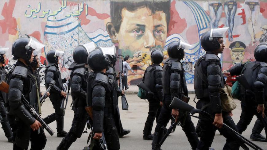 Riot police walk in front of graffiti representing anti-military power and Egypt's unrest, which reads "Glory to the unknown", along Mohamed Mahmoud Street during the third anniversary of violent and deadly clashes near Tahrir Square in Cairo November 19, 2014. Egyptian police arrested 25 individuals after four hundred protestors staged a march through downtown Cairo on the anniversary of deadly clashes with security forces three years ago, the interior ministry said on Wednesday.  REUTERS/Amr Abdallah Dals