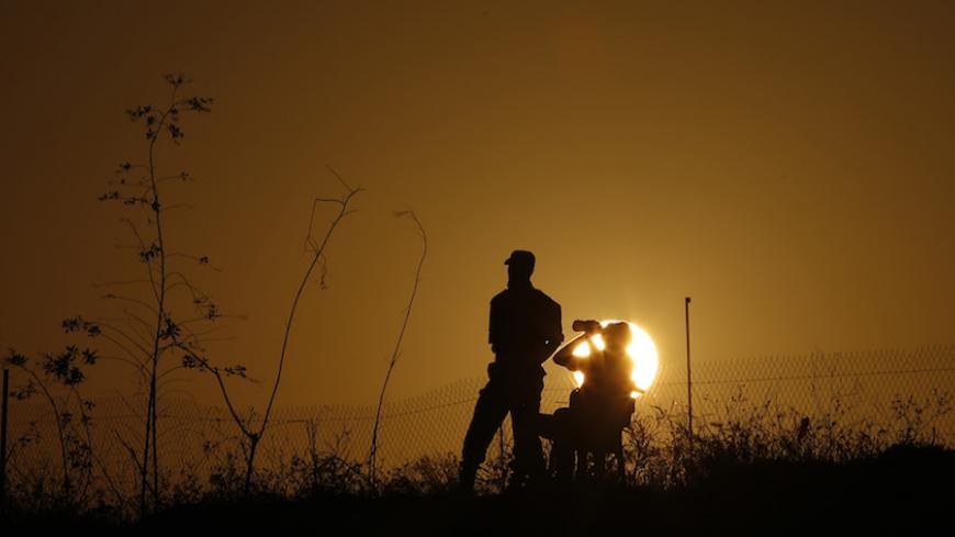A Palestinian Islamic Jihad militant drinks water as another stands guards during a military drill at sunset in the southern Gaza Strip December 11, 2014.  REUTERS/Suhaib Salem (GAZA - Tags: POLITICS CIVIL UNREST MILITARY) - RTR4HNV1