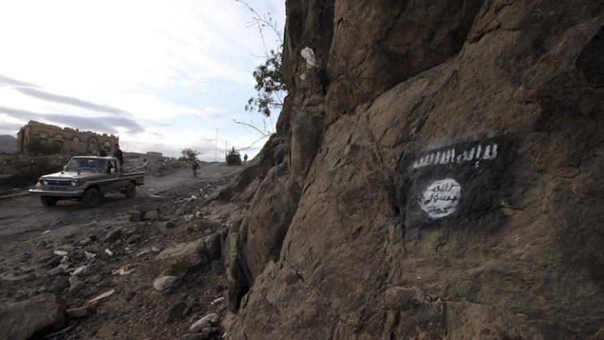 Shi'ite Houthi rebels drive a patrol truck past an Ansar al-Sharia flag painted on the side of a hill, along a road in Almnash, the main stronghold of Ansar al-Sharia, the local wing of Al Qaeda in the Arabian Peninsula (AQAP) in Rada, Yemen November 22, 2014.    To match Special Report YEMEN-AQAP/    REUTERS/Mohamed al-Sayaghi - RTSE50J