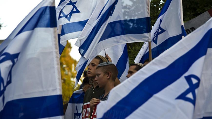 Right-wing activists hold Israeli national flags during a demonstration calling on the Israeli government to take action against recent violence in Jerusalem July 1, 2015.  REUTERS/Ronen Zvulun  - RTX1INCU