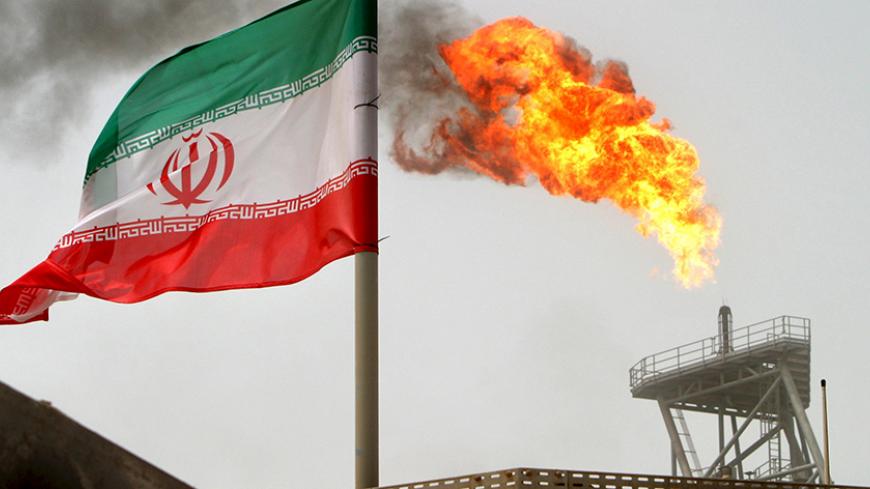 A gas flare on an oil production platform in the Soroush oil fields is seen alongside an Iranian flag in the Gulf July 25, 2005. REUTERS/Raheb Homavandi/File Photo - RTX2AOPF