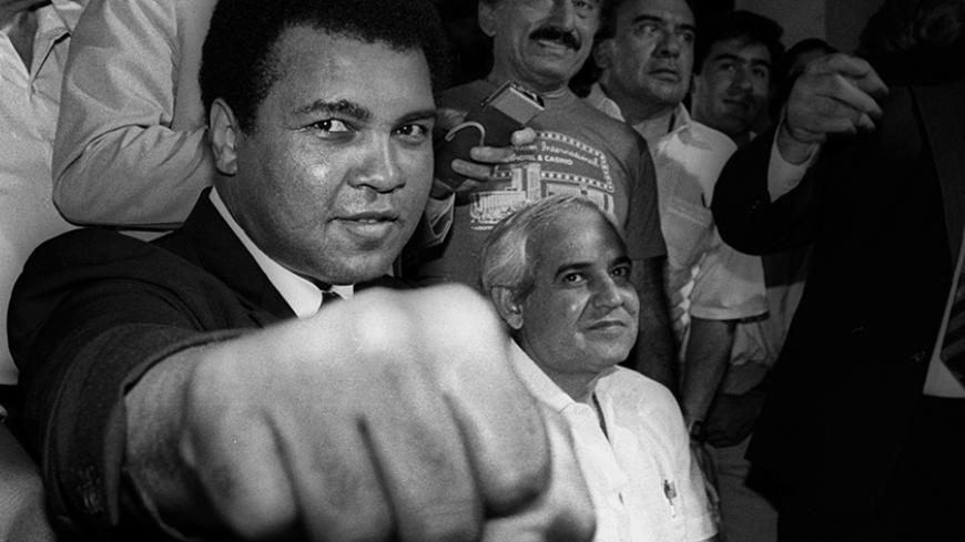 A smiling Muhammad Ali shows his fist to reporters during an impromptu press conference in Mexico City July 9, 1987.  REUTERS/Jorge Nunez - RTR1N6MB