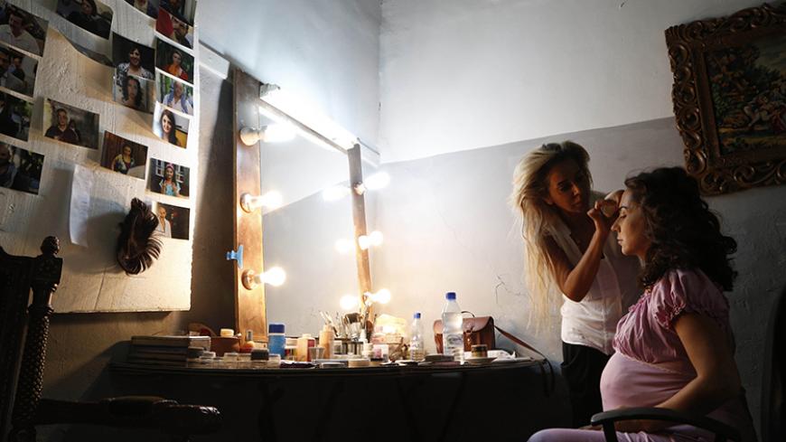 An actress has her make-up applied before the filming of a scene in an episode of Syrian TV series "Al-Haqaeb - Dhubou al-Shanatee" (Baggage - Pack Your Bags), directed by Al-Laith Hajjo, at the set location in old Damascus July 6, 2014. As conflict continues in Syria, the group of actors is literally risking their lives to bring drama to television screens. Like many Syrian dramas filmed over the last three years, the TV series focuses on the life of a Syrian family living through the war. Picture taken Ju