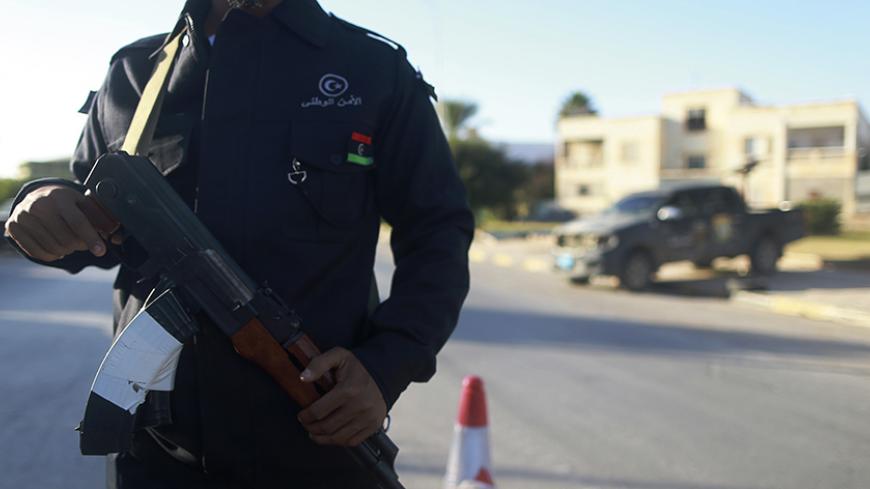 A security officer stands with his weapon on a road leading to a police station in Benghazi December 4, 2014. Police stations, prisons and the local security headquarters have reopened in Libya's eastern city of Benghazi for the first time in over a year, officials said, after pro-government forces seized back part of the port city. Medics say around 450 people have been killed in a two-month offensive by pro-government forces which has restored some sense of normality in parts of the city, though fighting 