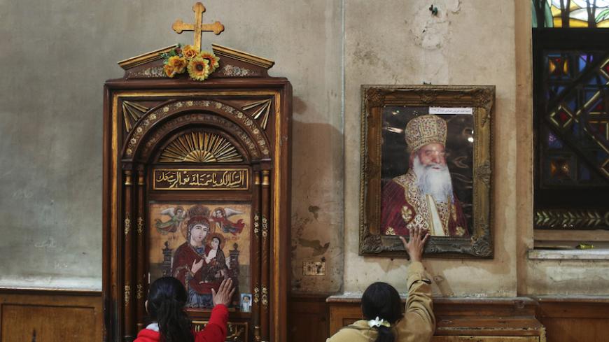  Coptic Orthodox Christians touch the pictures of the Virgin Mary and Jesus (L) and  Pope St. Kyrillos VI for blessings after a religious session by Father Makary at St Mark Catedral in Cairo January 2, 2015. Father Makary Younan is one of the most popular among the Coptic Egyptians to practice exorcism. Picture taken January 2, 2015. REUTERS/Asmaa Waguih (EGYPT - Tags: RELIGION SOCIETY) - RTR4JXRE