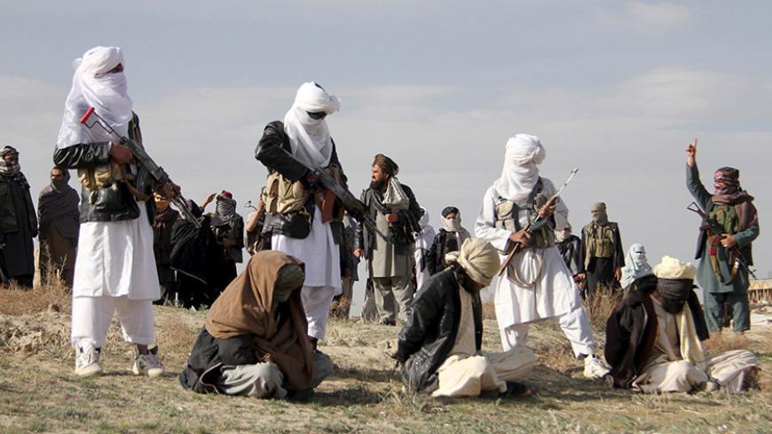 Taliban insurgents stand over three men, accused of murdering a couple during a robbery, before shooting them during their execution in Ghazni Province April 18, 2015. The Taliban announced the execution of the three men accused of murdering a couple during a robbery, saying they had been tried by an Islamic court. The killing was carried out in front of a crowd by Taliban fighters who fired at the men with AK-47s, according to a Reuters witness. Footage seen by Reuters show the men were made to sit on the 