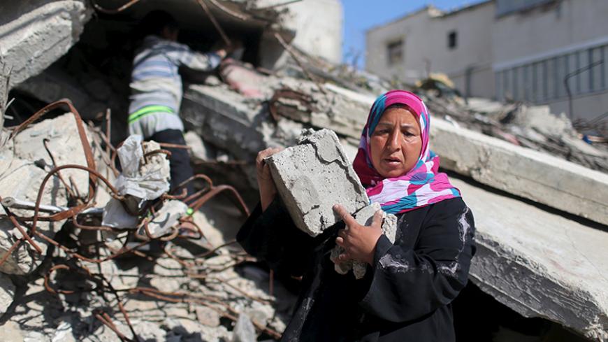 Palestinian woman Jihan Abu Muhsen collects bricks for sale with her son Mohammad from the ruins of a house destroyed during the 2014 war in Khan Younis in the southern Gaza Strip March 8, 2016. Abu Muhsen gathers bricks from the sites of demolished buildings and sells them to recycling factories. She earns around 20 shekels ($5) a day and her 10-year-old son Mohammad helps her when he is not at school. REUTERS/Ibraheem Abu Mustafa    SEARCH "GAZA BRICK" FOR THIS STORY. SEARCH "THE WIDER IMAGE" FOR ALL STOR