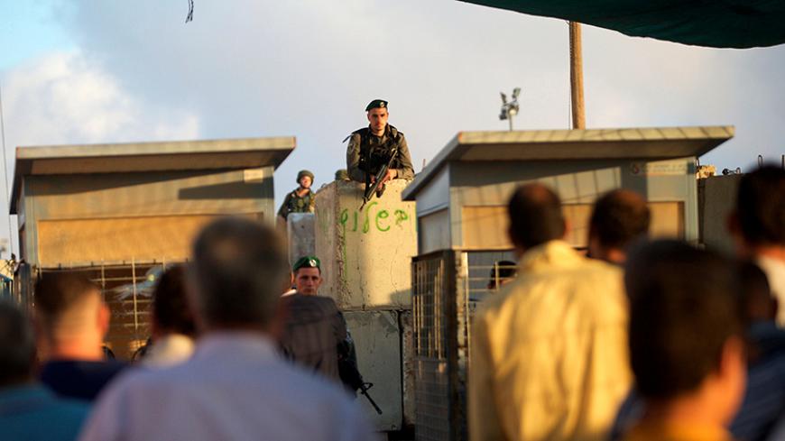 Israeli border police officers stand guard as Palestinians wait to cross through the Qalandia checkpoint to make their way to attend the first Friday prayer of the holy fasting month of Ramadan in Jerusalem's al-Aqsa mosque, near the West Bank city of Ramallah June 10, 2016. REUTERS/Mohamad Torokman - RTSGUJL