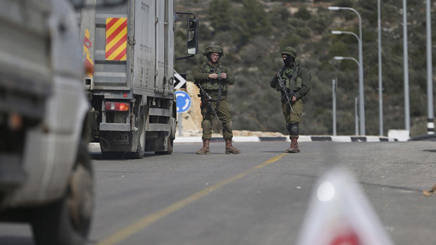Israeli soldiers stand guard as they carry out an identity check on Palestinians at an Israeli checkpoint leading to the West Bank city of Ramallah February 1, 2016. Following Sunday's shooting attack by a Palestinian, Israeli forces have taken security measures allowing only residents of Ramallah to enter the city, with a temporary closure for exit except for humanitarian cases, an Israeli military spokeswoman said. REUTERS/Mohamad Torokman  - RTX24W9B