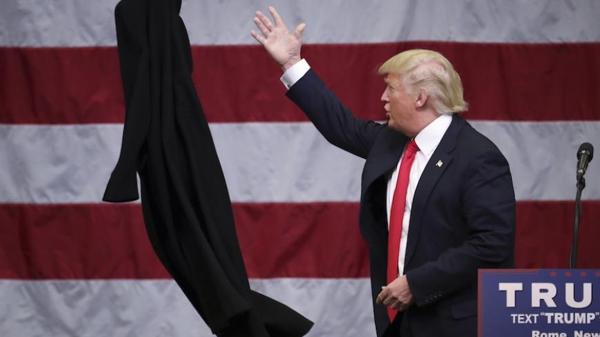 U.S. Republican presidential candidate Donald Trump tosses off his overcoat as he speaks at a campaign event in an airplane hangar in Rome, New York April 12, 2016. REUTERS/Carlo Allegri      TPX IMAGES OF THE DAY      - RTX29ODW