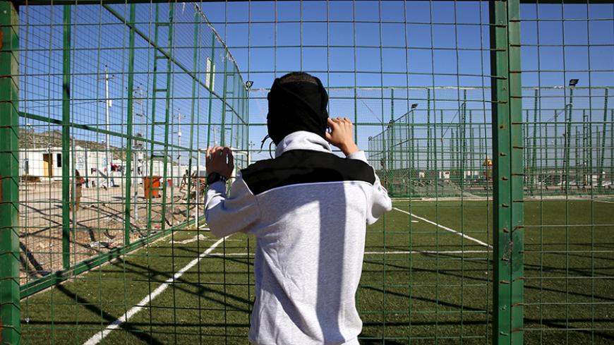 A Yazidi boy, 16, who was trained by Islamic State, wraps his head in a scarf as he stands by the fence of a playground at a refugee camp near the northern Iraqi city of Duhok April 19, 2016. The stories of boys from the minority Yazidi community now living in a refugee camp near the northern Iraqi city of Duhok appear to show efforts by Islamic State to create a new generation of fighters loyal to the group's ideology and inured to its extreme violence. The training often leaves them scarred, even after re